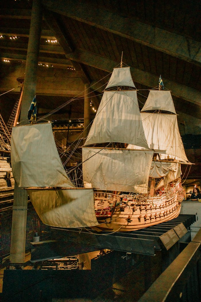 Home Large historic ship indoors at a maritime museum with dramatic lighting.